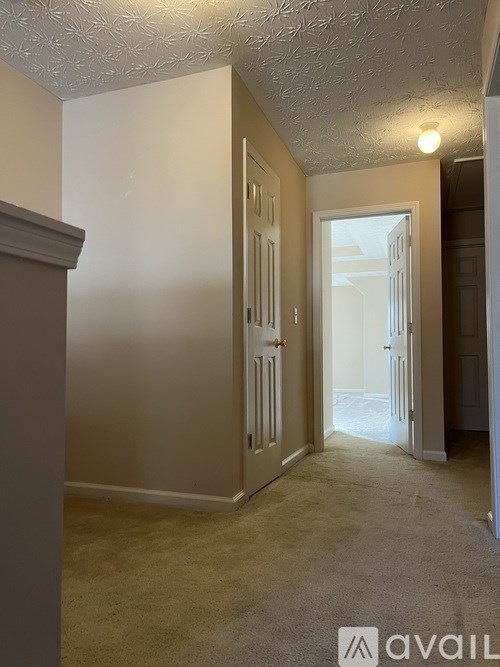 A hallway with a carpeted floor and a doorway leading to another room.