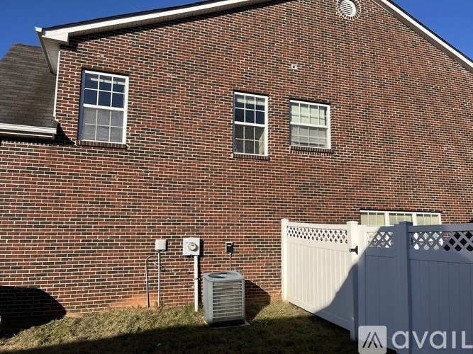 A red brick house with a white fence in front.