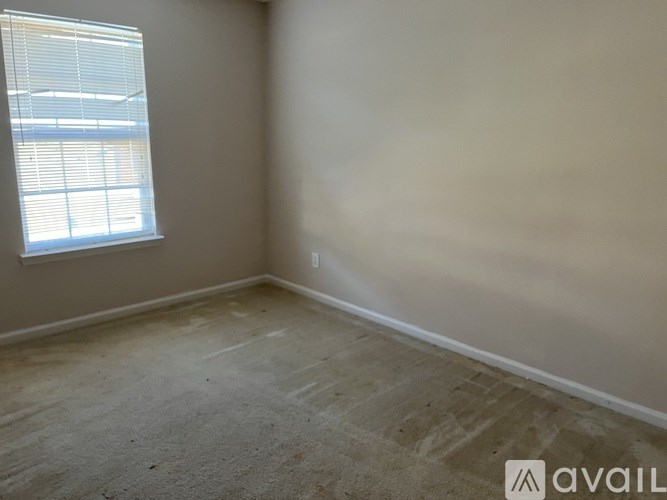 A room with a window and a carpeted floor.
