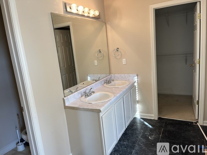 A bathroom with a vanity, mirror, and lights.