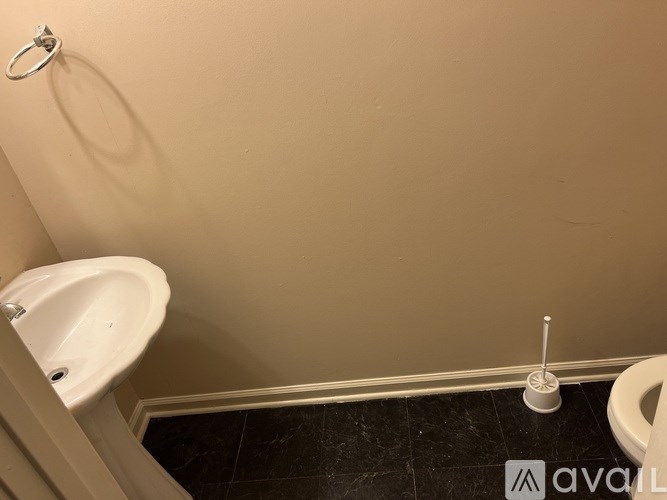 A white sink is on the left of a toilet in a bathroom.