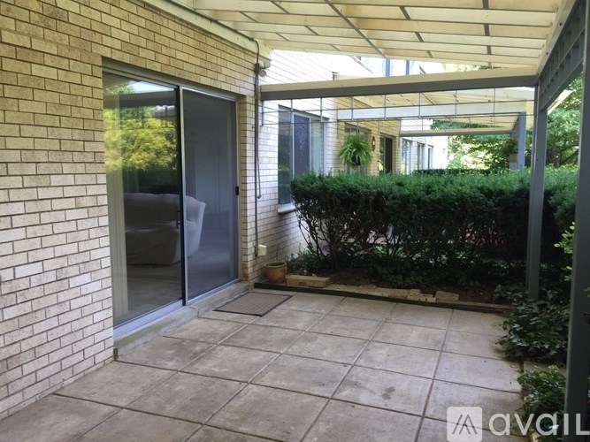 A patio area with a glass door and a brick wall.