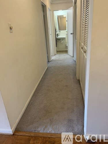 A hallway with a carpeted floor and white walls.