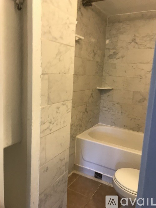 A bathroom with a toilet, tub and marble tiles.