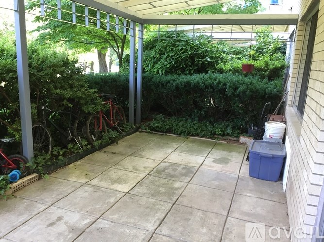 A patio with a white tile floor and a bicycle leaning against a wall.