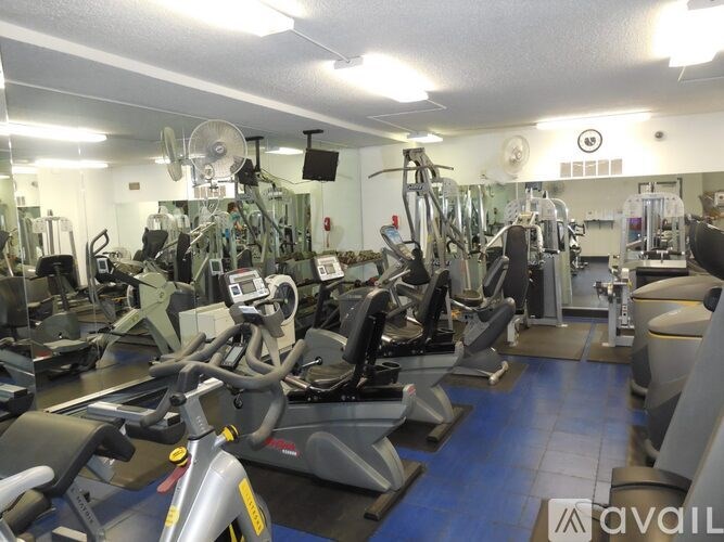 A gym with a variety of exercise equipment including treadmills, stationary bikes, and weight machines.