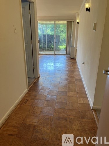A hallway with wooden flooring and a door leading to a balcony.