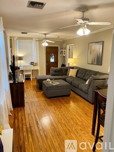 A living room with a grey couch and a wooden floor.
