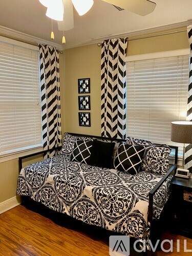 A black and white patterned sofa in a room with a window covered by blinds.