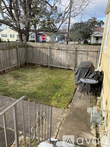 A backyard with a fence, a chair, and a table.