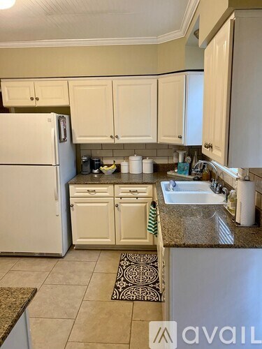 A kitchen with a white refrigerator and cabinets.
