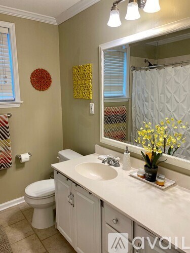 A bathroom with a toilet, sink, mirror, and a vase of flowers.