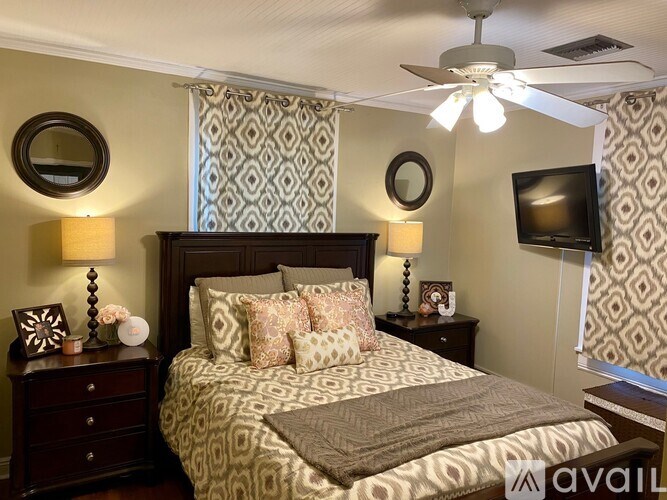 A bedroom with a patterned bedspread and a ceiling fan.