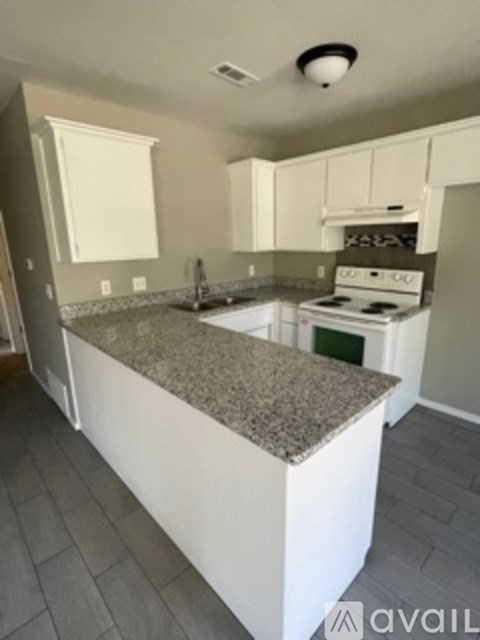 A kitchen with granite countertops and white cabinets.