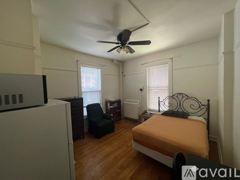 A bedroom with a bed, chair, and ceiling fan.