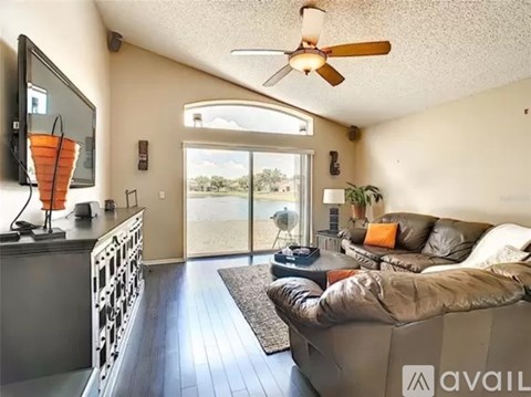 A living room with a grey couch and a flat screen TV mounted on the wall.