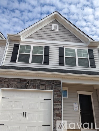A house with a white garage door and a stone wall.