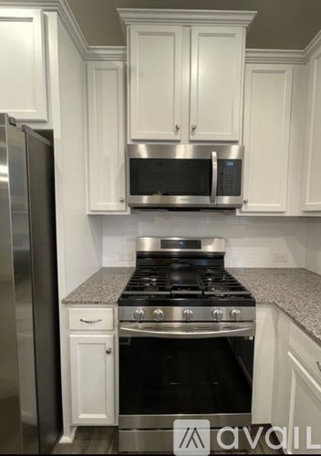 A kitchen with white cabinets and a stainless steel refrigerator.