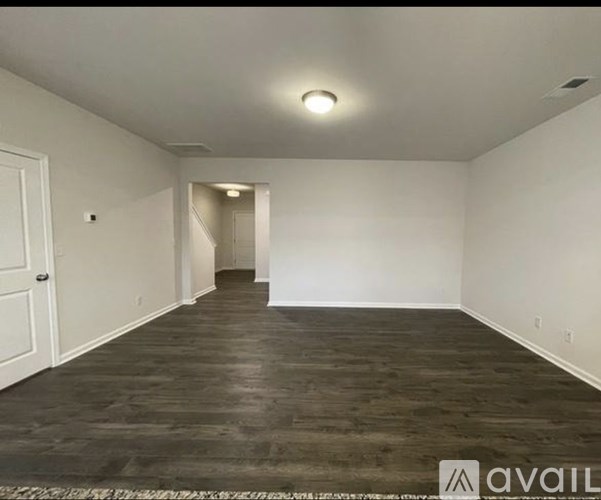 A spacious room with a white door and a white wall.