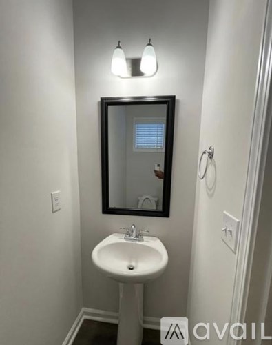 A bathroom with a sink, mirror, and light fixture.
