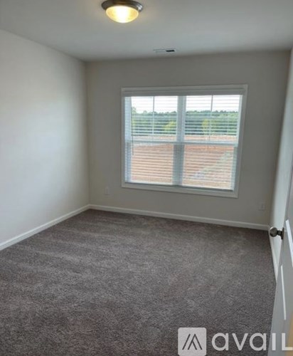 A room with a carpeted floor and a window with blinds.