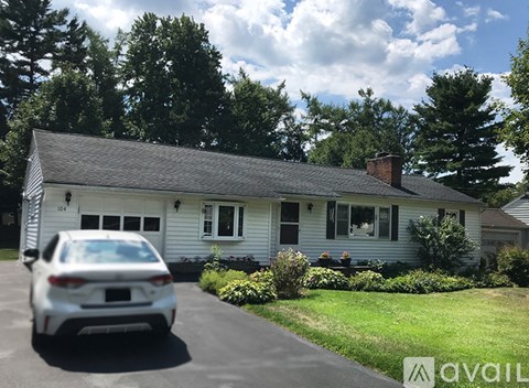 A white car is parked in front of a house.