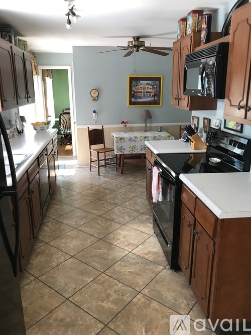 A kitchen with a tile floor and a ceiling fan.