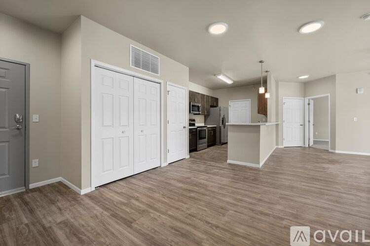 A spacious room with wooden flooring and a kitchen area in the background.
