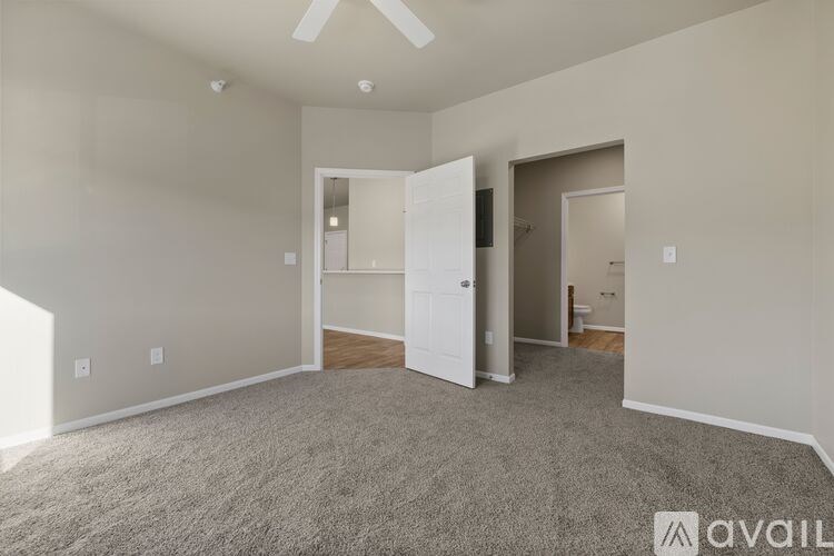 A spacious room with a carpeted floor and a ceiling fan.
