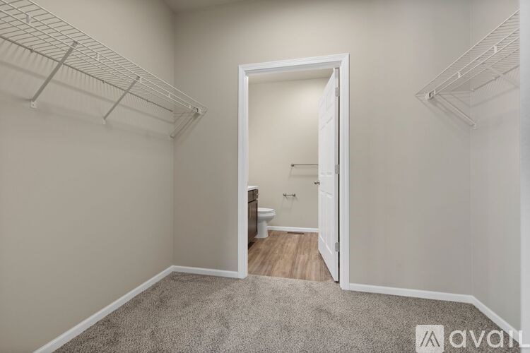 A room with white walls and a carpeted floor with a doorway leading to another room.