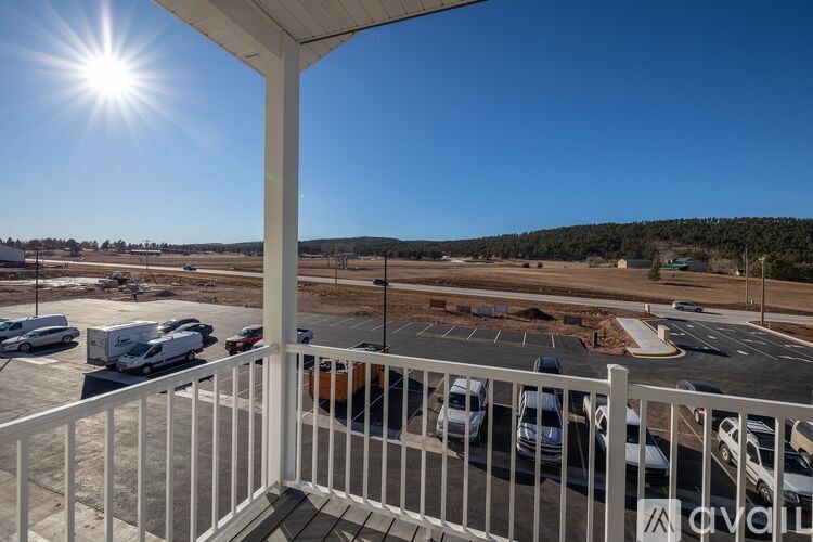 A sunny day at the parking lot with cars parked and a white railing in the foreground.