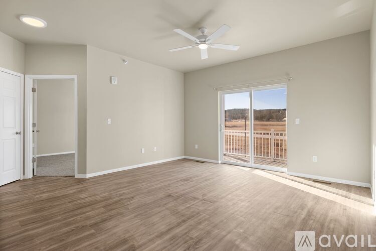 A spacious room with a ceiling fan and sliding glass doors leading to a balcony.