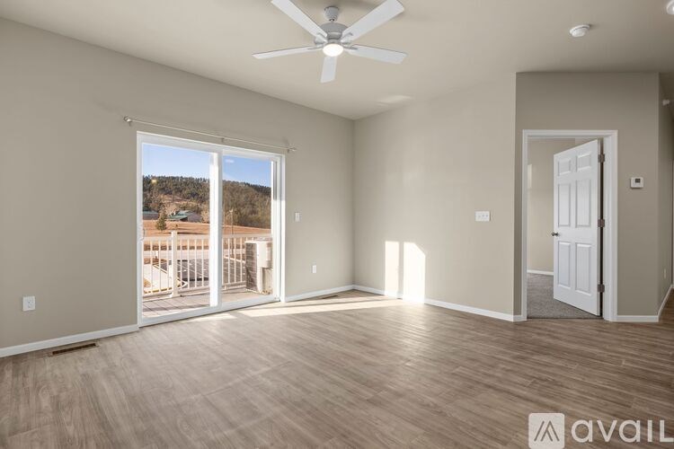 A room with a ceiling fan and sliding glass doors leading to a balcony.