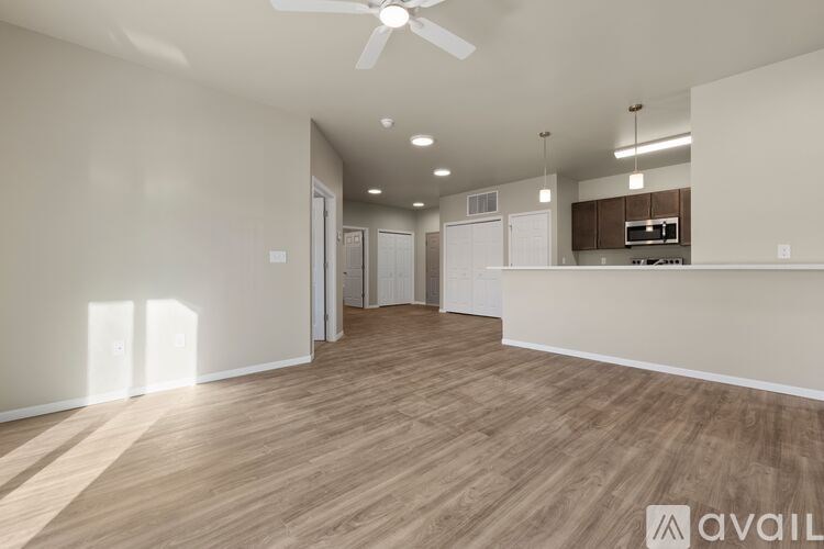A spacious room with wooden flooring and a ceiling fan.