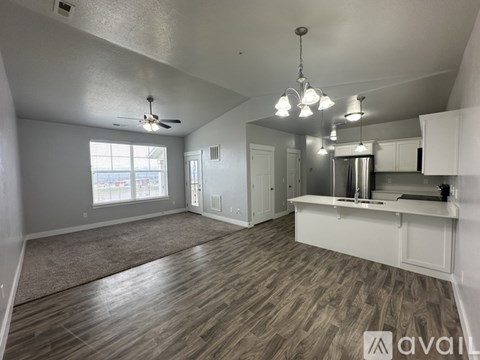 A spacious kitchen and living room with wood flooring and white cabinetry.