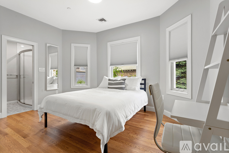 A bedroom with a white bed and a wooden floor.