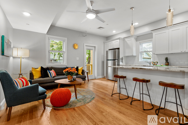 A living room with a grey couch, a red ball, and a wooden floor.