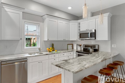 A kitchen with white cabinets and a marble countertop.