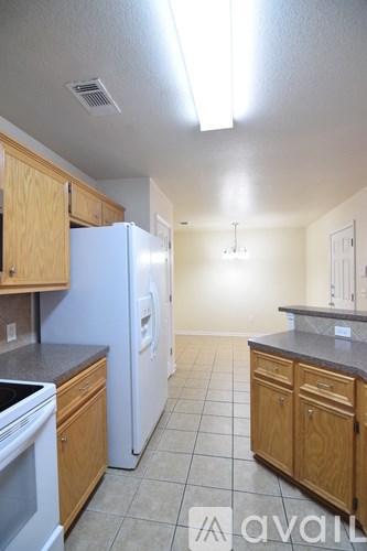 A kitchen with a white refrigerator and wooden cabinets.