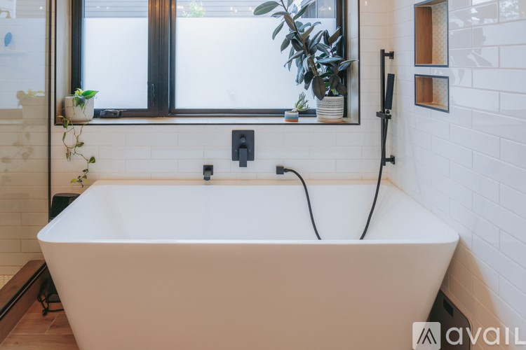 A white bathtub is in a bathroom with a window above it.