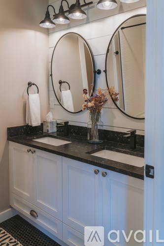 A bathroom with a sink, mirrors, and a vase of flowers.