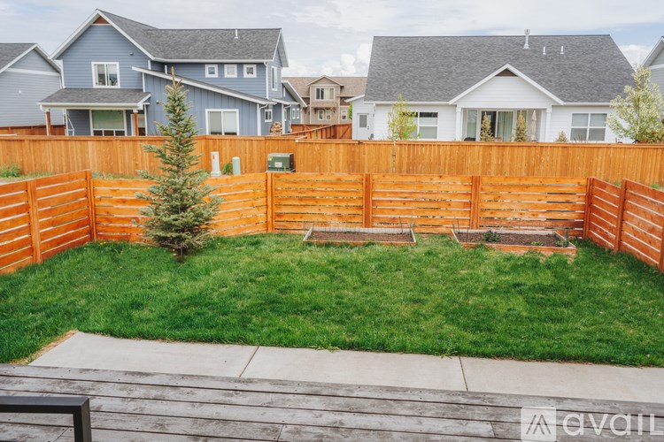 A backyard with a wooden fence and a green lawn.