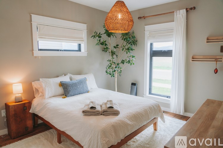 A bedroom with a large bed, a wooden nightstand, and a hanging plant.