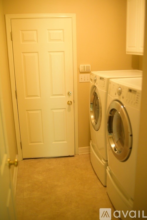 A white door is next to a washer and dryer in a small room.