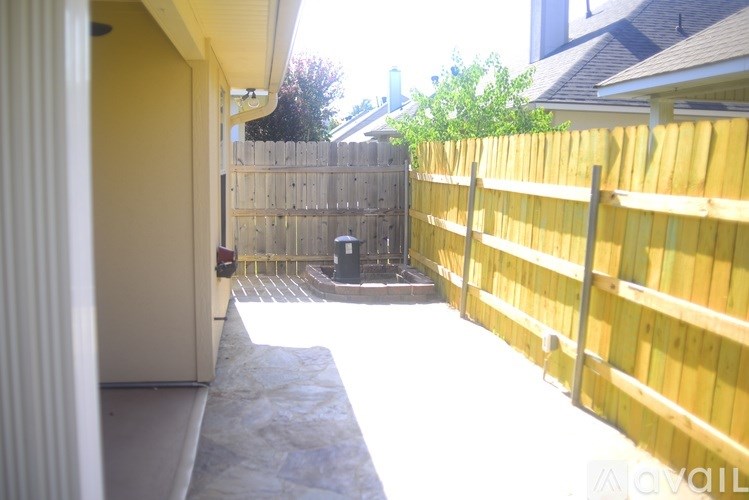 A backyard with a wooden fence and a small tree.