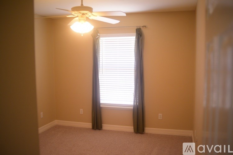 A room with a ceiling fan and a window with curtains.