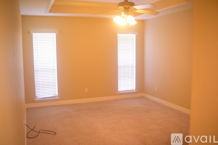 A room with a ceiling fan and two windows with blinds.