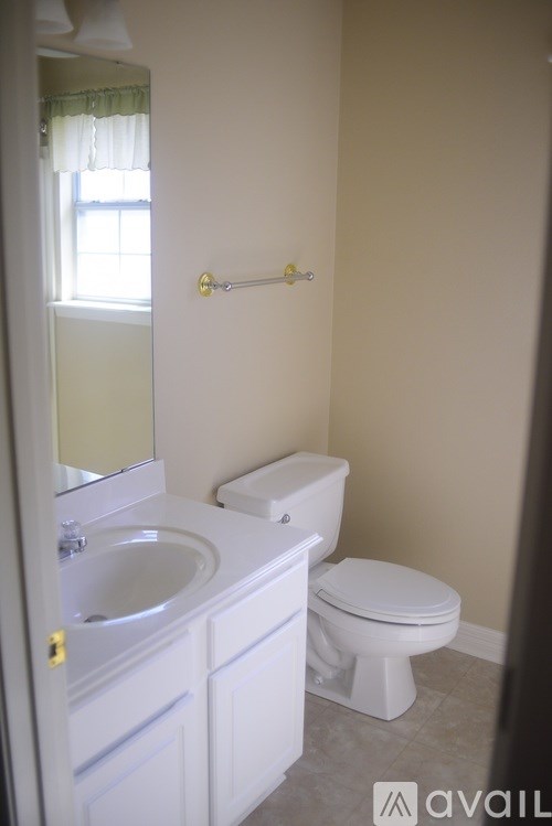A bathroom with a toilet, sink, and mirror.