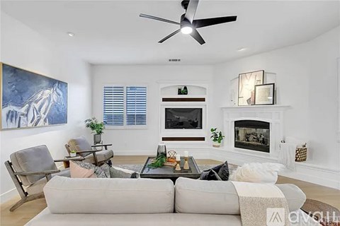 A living room with a grey couch, a coffee table, a fireplace, and a painting on the wall.