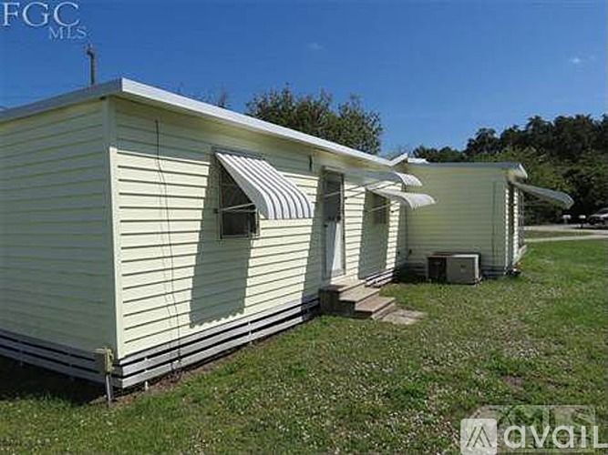 A row of mobile homes are lined up in a grassy field.